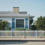 white and blue house beside fence