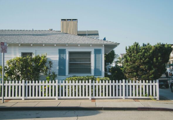 white and blue house beside fence