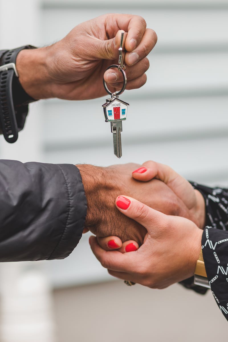 Close-up of a handshake with a house key, symbolizing real estate transactions.